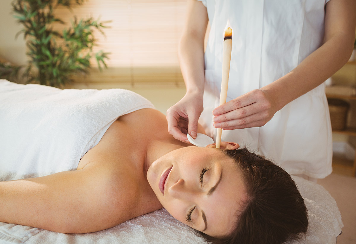 Young woman getting an ear candling treatment in therapy room