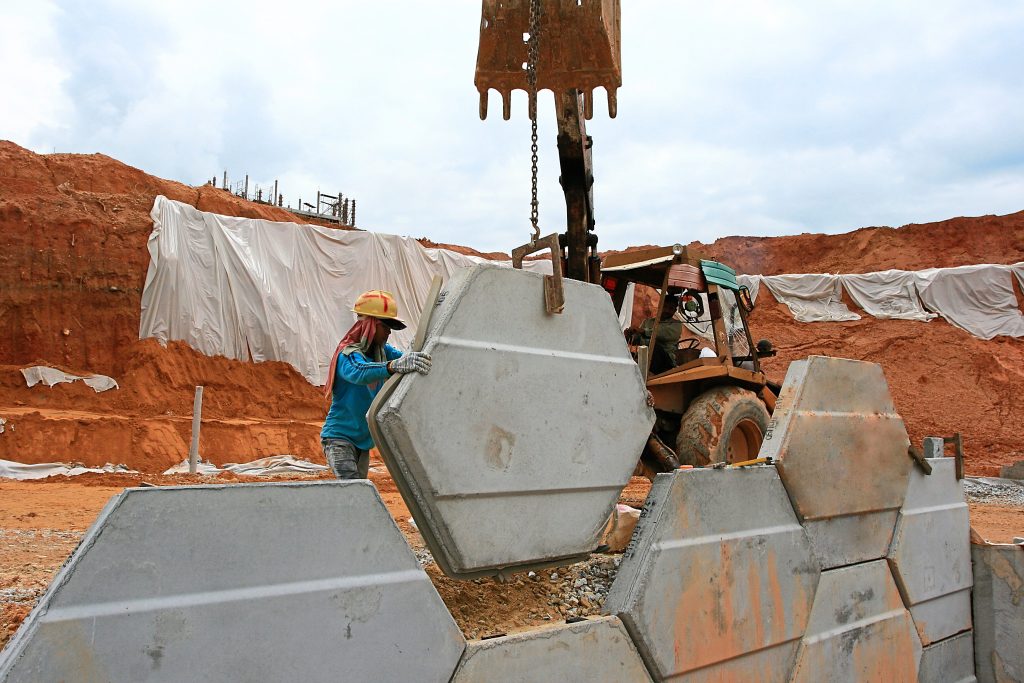 Workers installing the facing panels using reinforced soil technology.